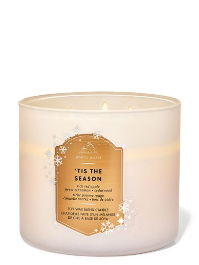 Svíčka „'Tis The Season“ v bílé matné nádobě se zlatou etiketou a sněhovými vločkami, Bath & Body Works.