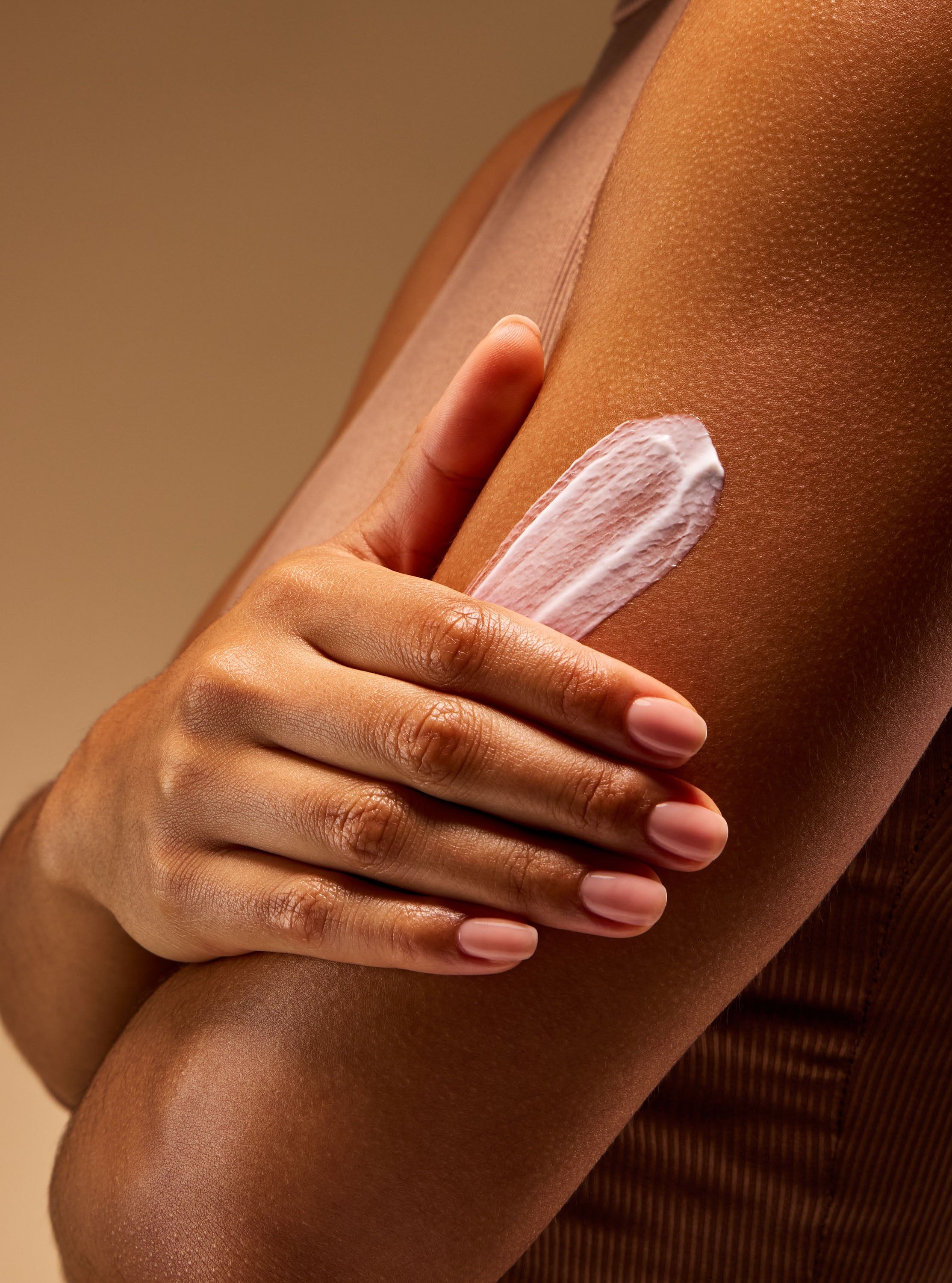 Mâna aplică cremă pe pielea brațului, evidențiind textura hrănitoare și efectul intens de hidratare.