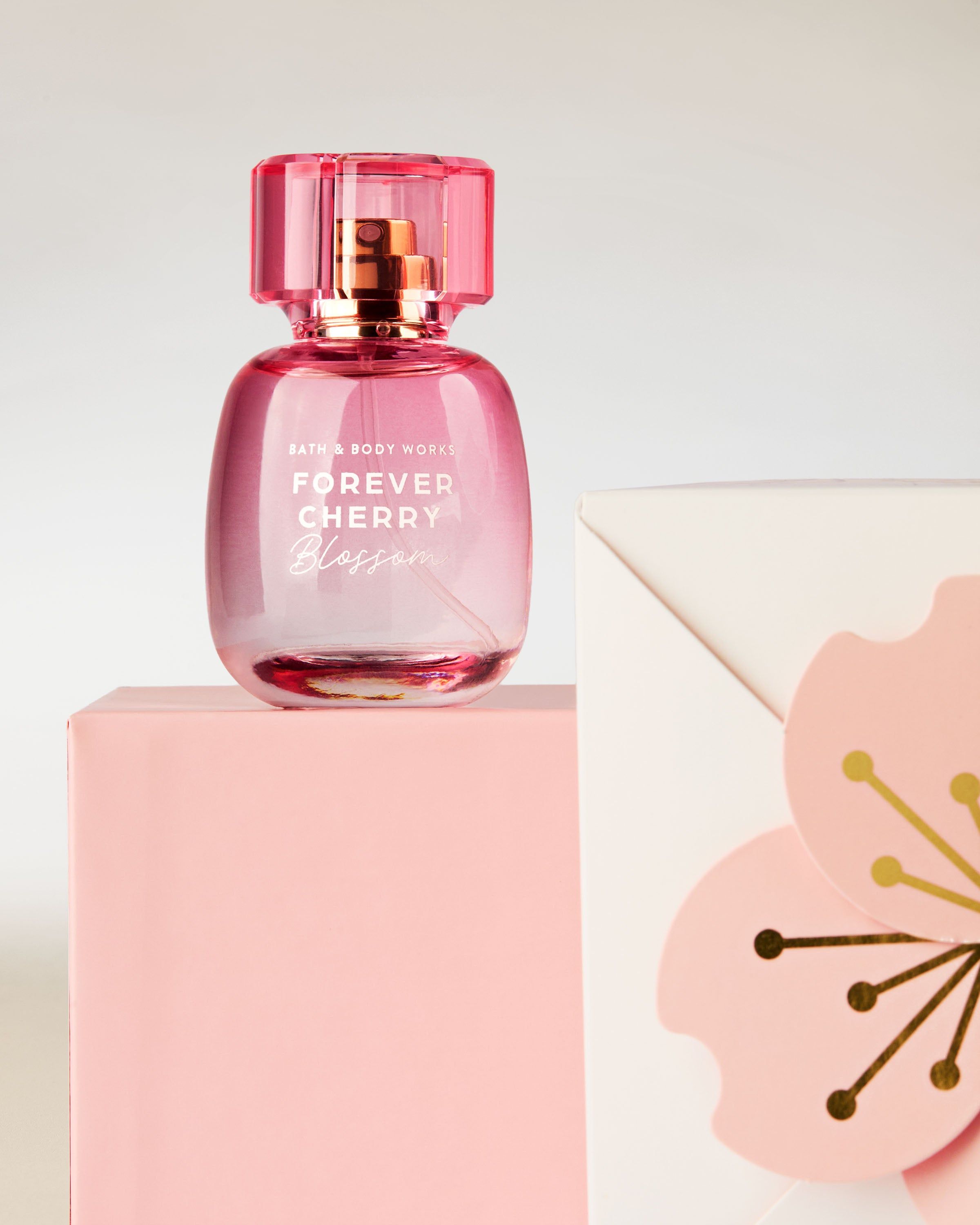 Parfum Bath & Body Works Forever Cherry Blossom, în flacon roz, pe fundal de flori de cireș.