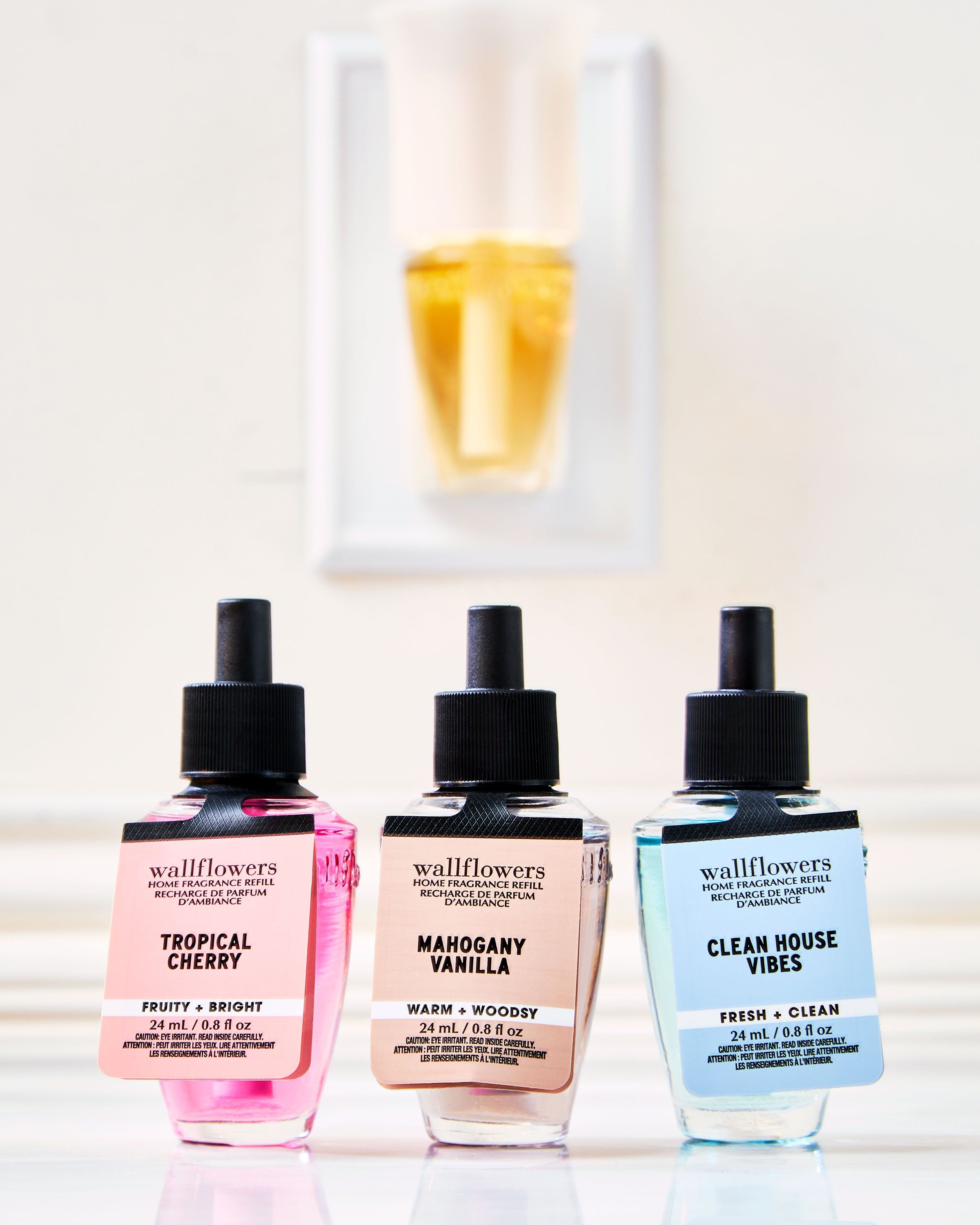 Set de trei reumpleri Wallflowers: Tropical Cherry, Mahogany Vanilla și Clean House Vibes în fața difuzorului.