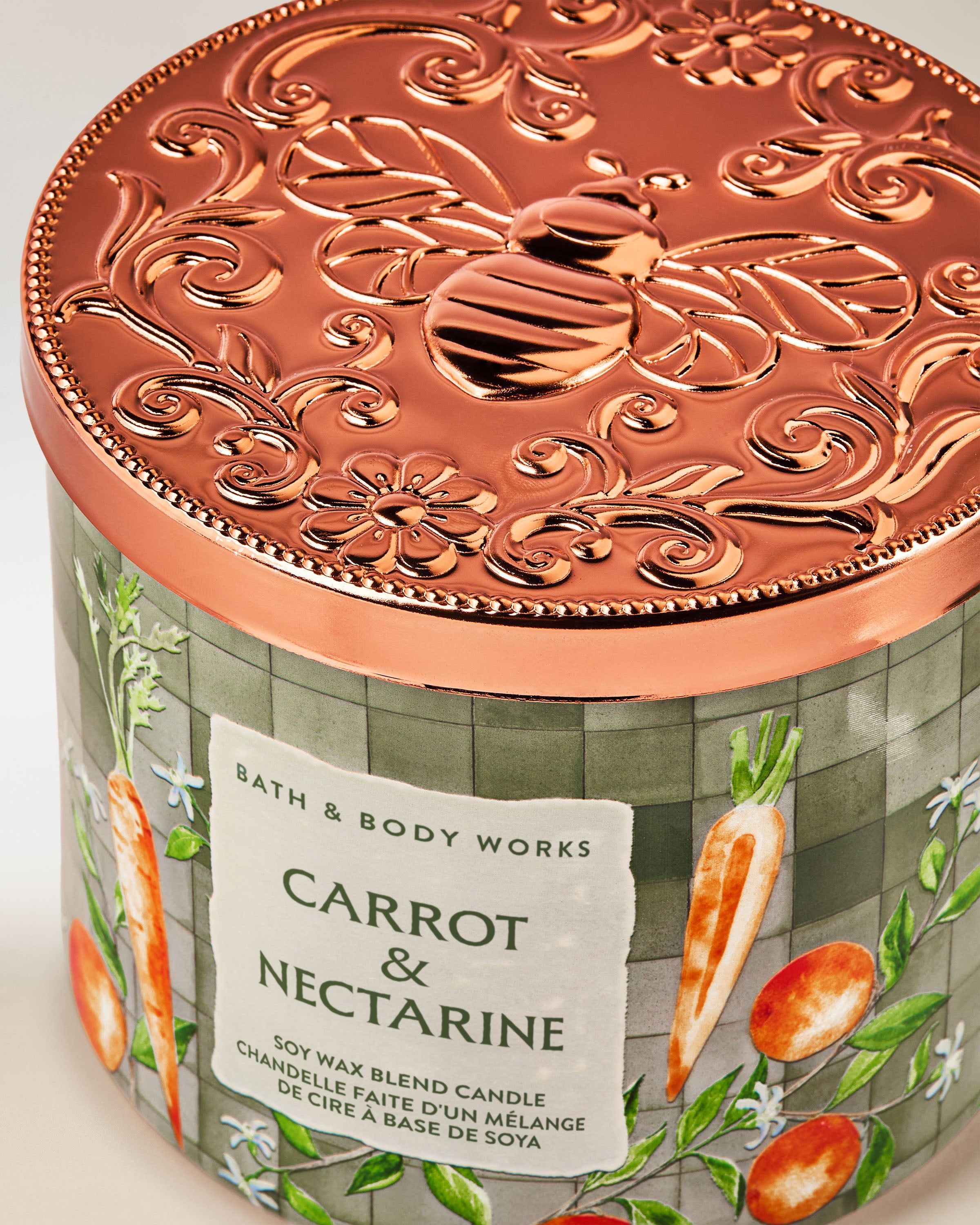 Lumânare parfumată cu 3 fitiluri Bath & Body Works Carrot & Nectarine, în recipient din sticlă cu motiv vegetal.