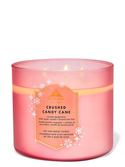 Růžová skleněná vonná svíčka „Crushed Candy Cane“ se třpytivými sněhovými vločkami na etiketě, Bath & Body Works.