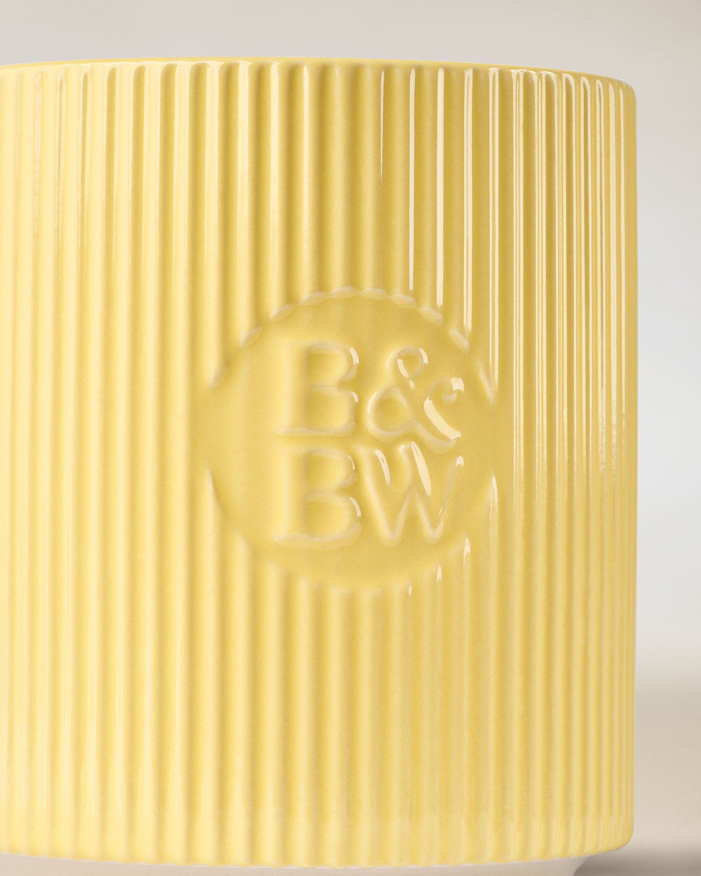 Lumânare Bath & Body Works în suport ceramic galben, cu textură striată.