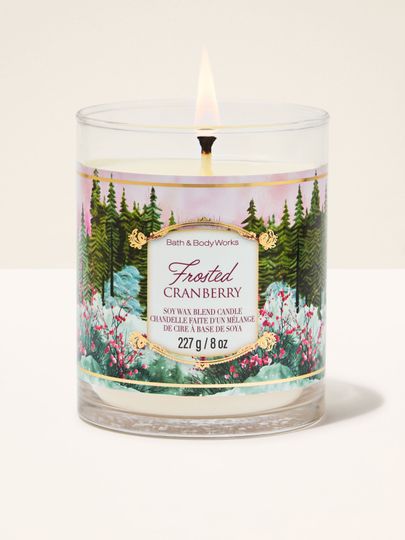 Lumânare parfumată Frosted Cranberry Bath & Body Works cu un fitil aprins și motiv de pădure de iarnă