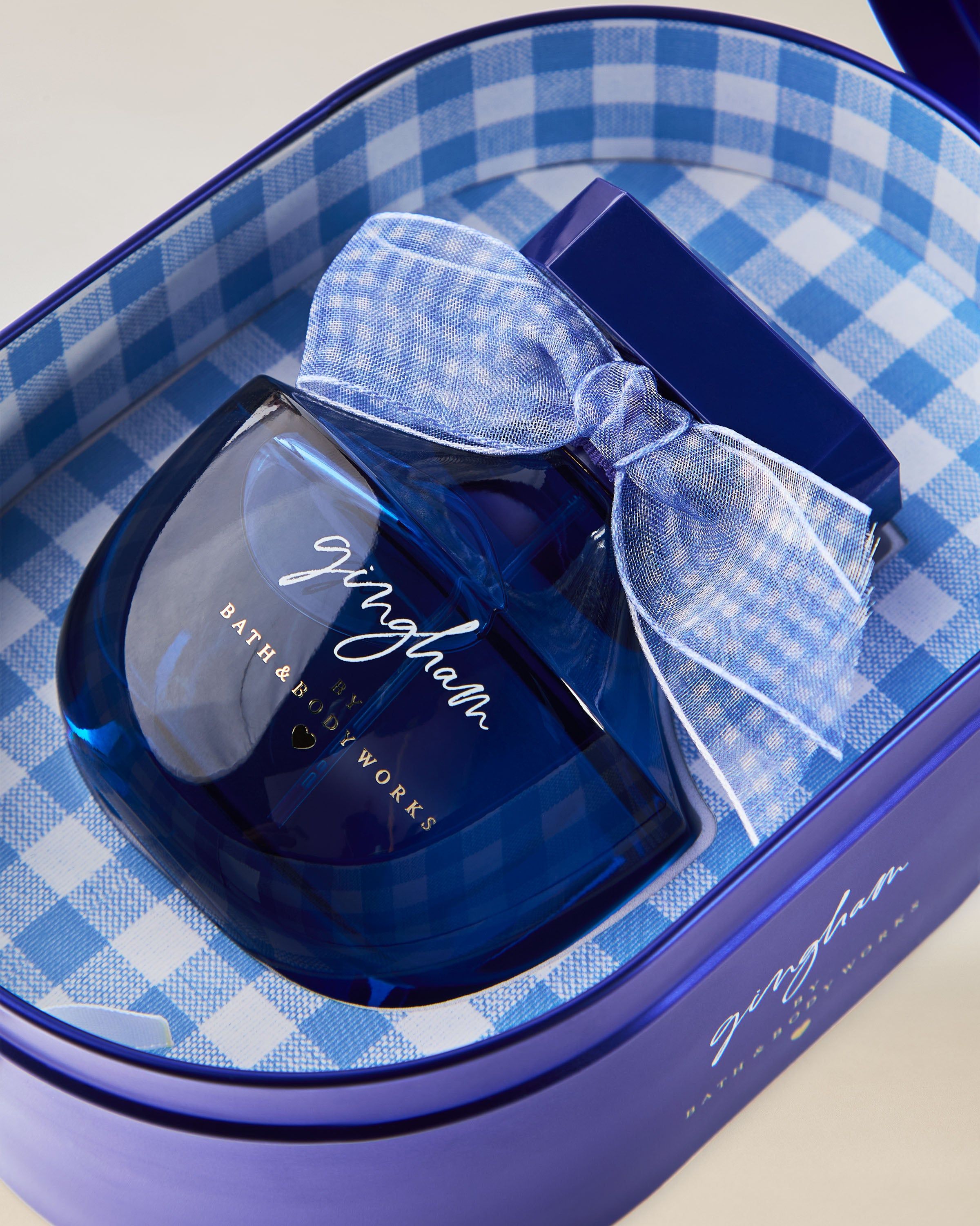 Parfum Bath & Body Works Gingham, în flacon albastru din sticlă cu fundă decorativă.