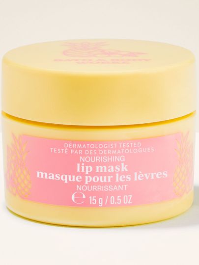 Borcan galben cu Nourishing Lip Mask, etichetă roz și detalii cu ananas, prezentat în cadru produs.