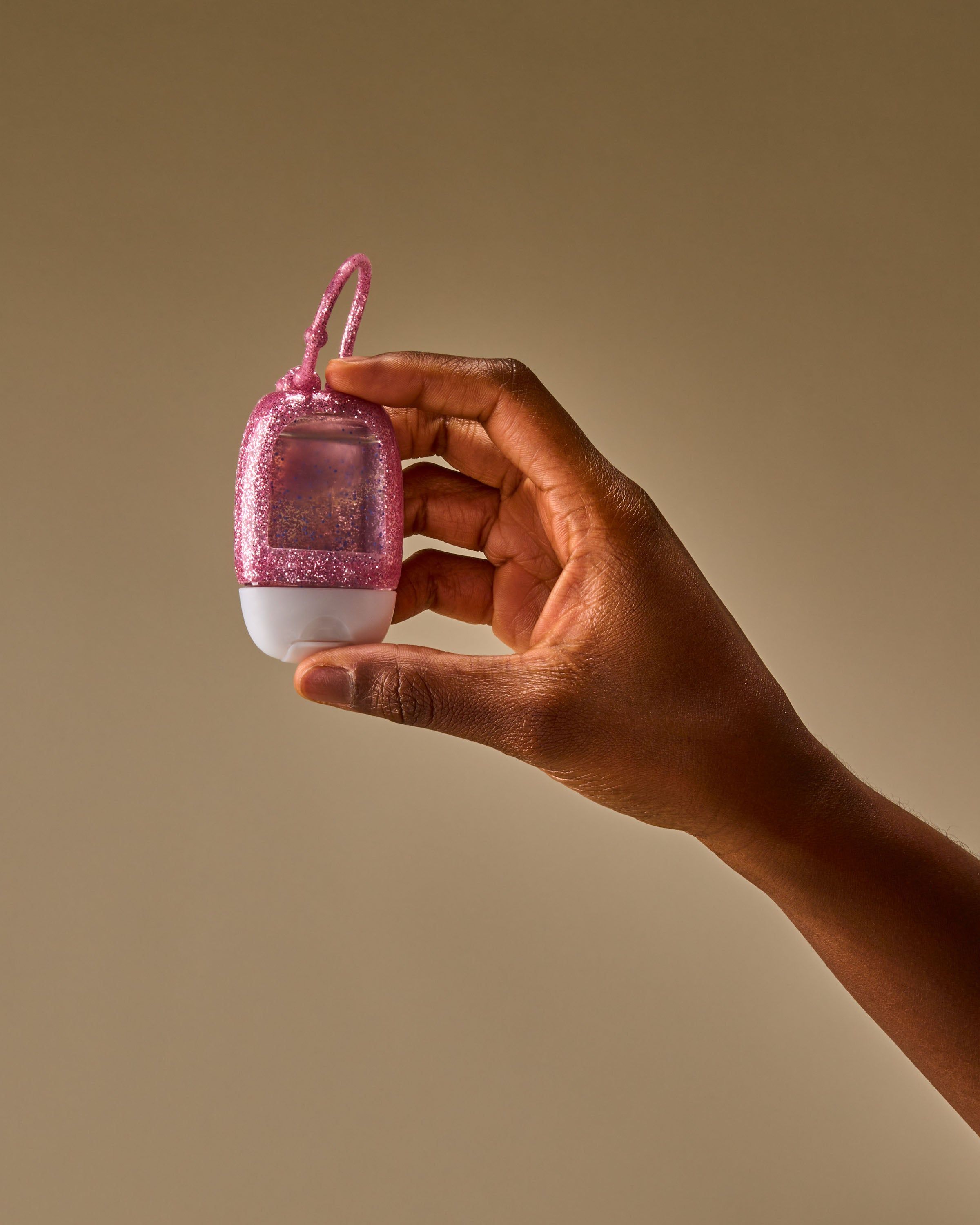 Cadru care arată suportul strălucitor PocketBac ținut în mână, evidențiind formatul compact și bucla flexibilă pentru prindere.