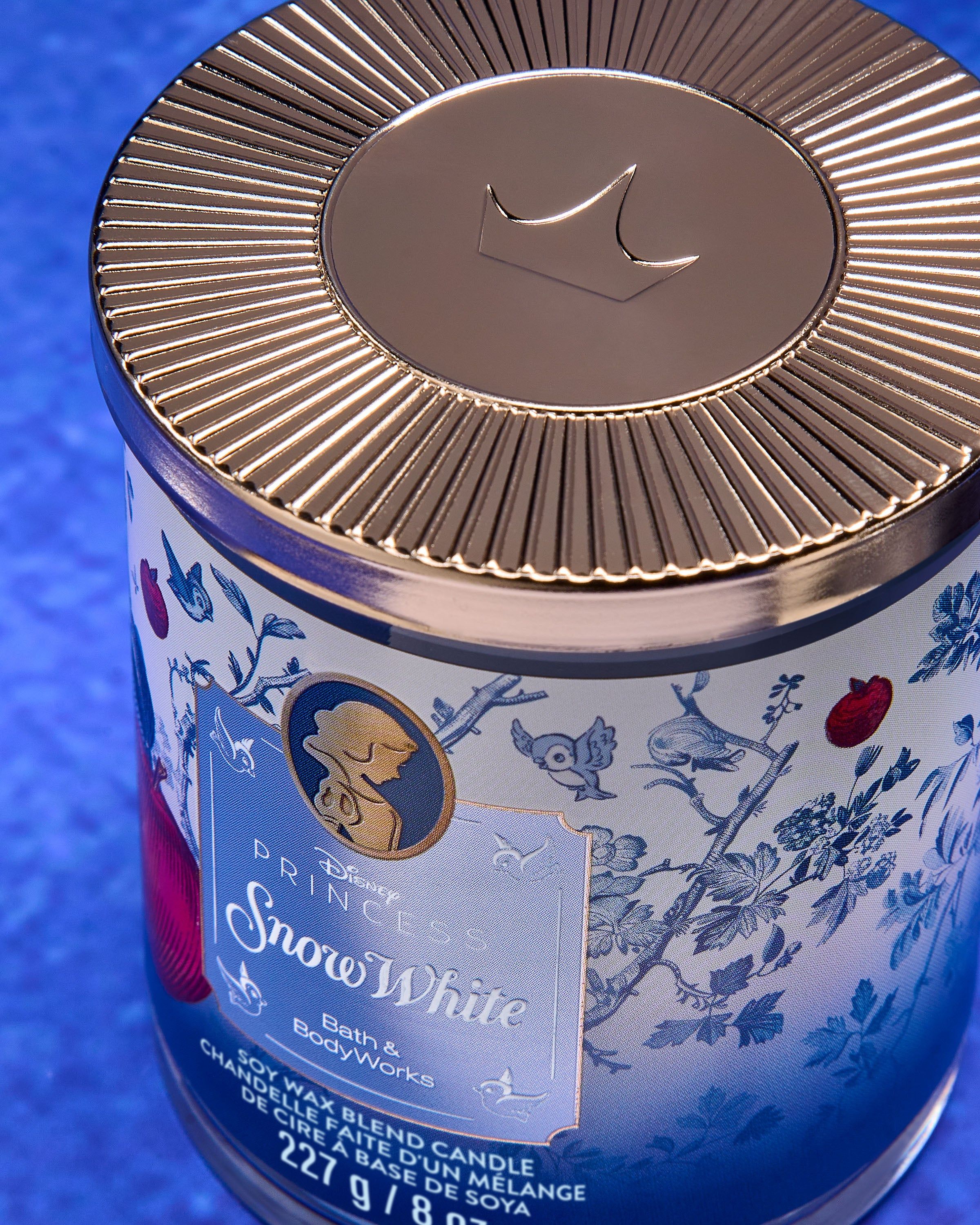 Świeca Snow White z kolekcji Disney Princess — niebieski design z jabłkiem i leśnymi detalami.