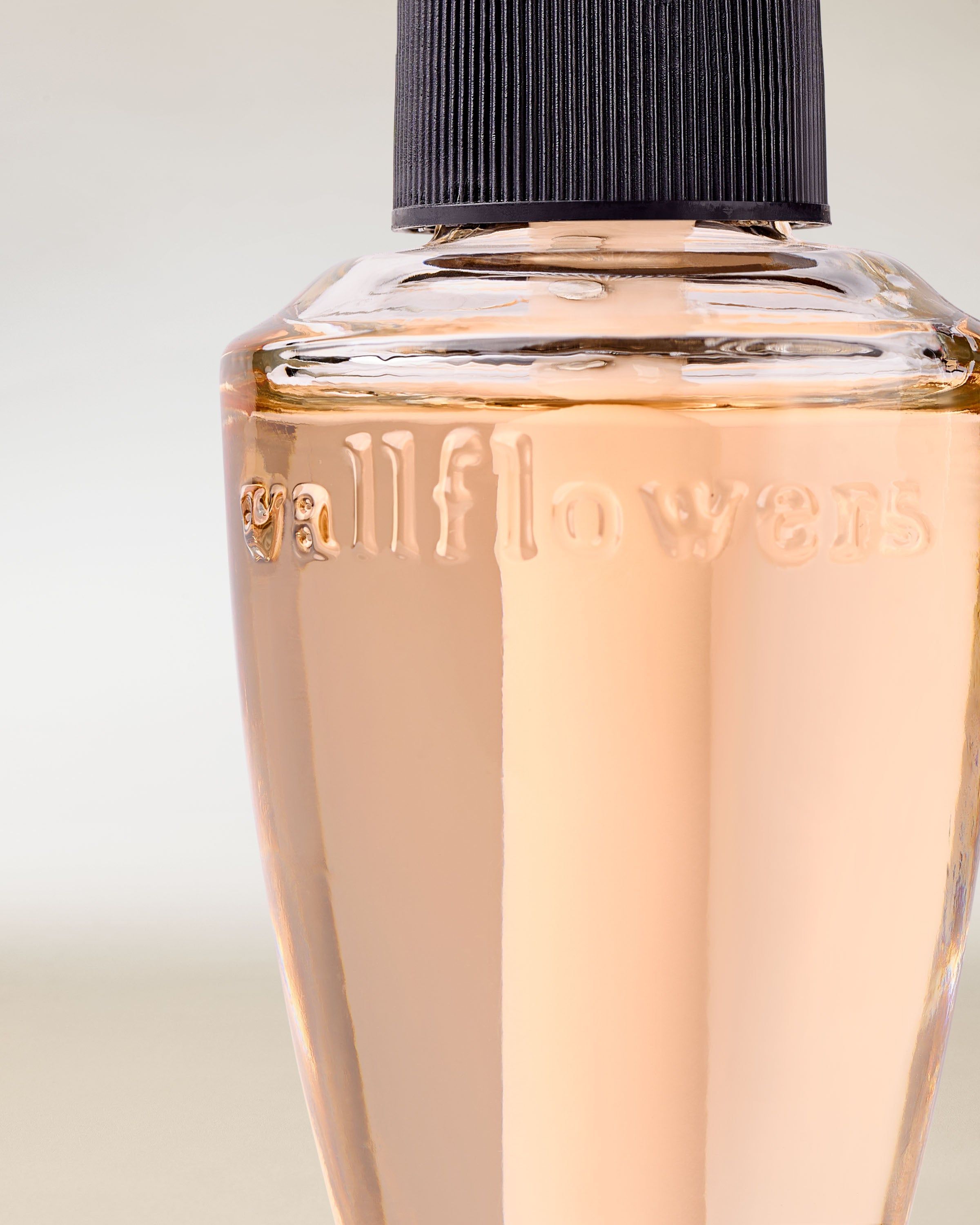 Rezeră Wallflowers în prim-plan, cu lichid strălucitor și un design elegant, minimalist.