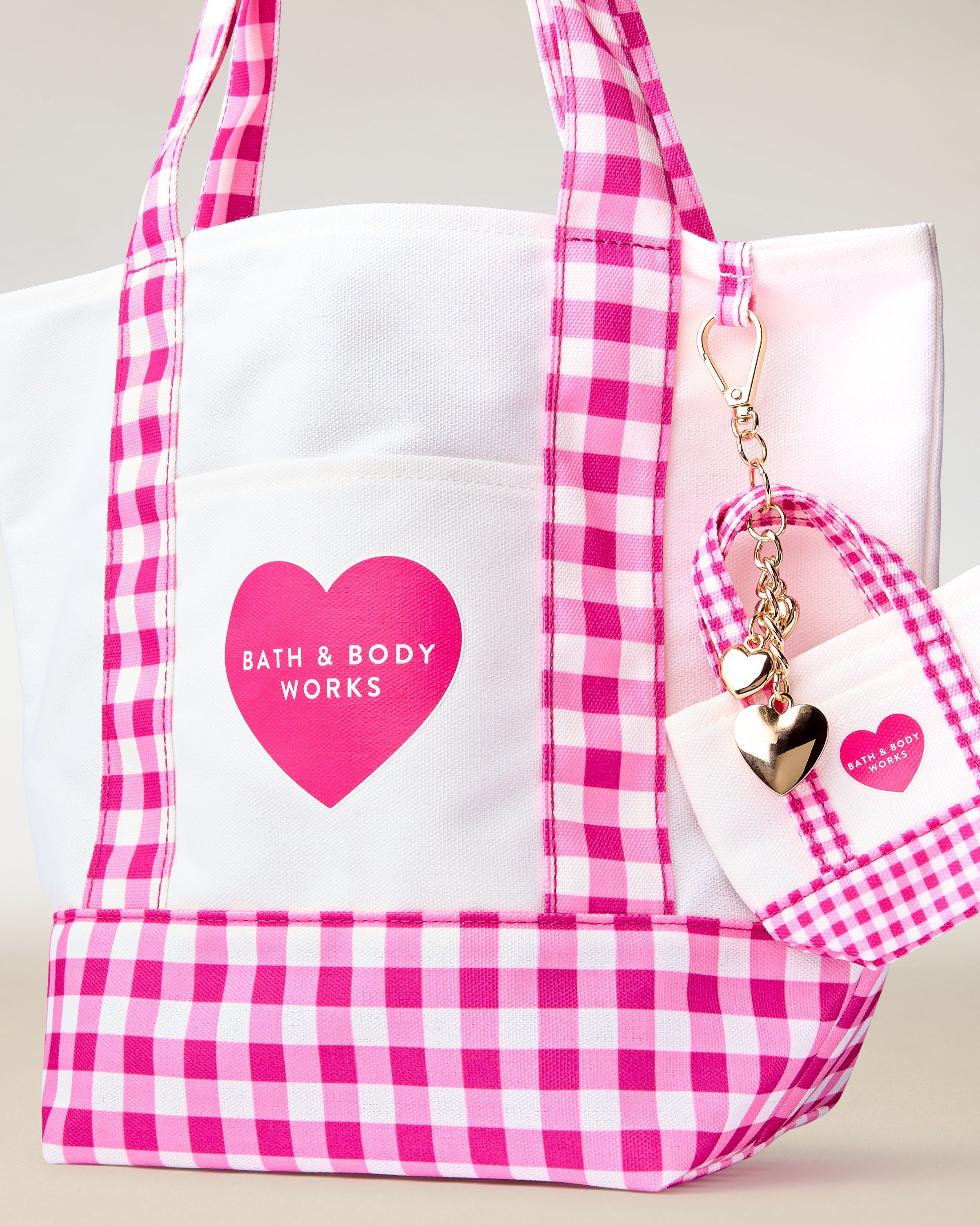 Geantă Bath & Body Works cu model gingham roz‑alb, mânere și breloc decorativ.
