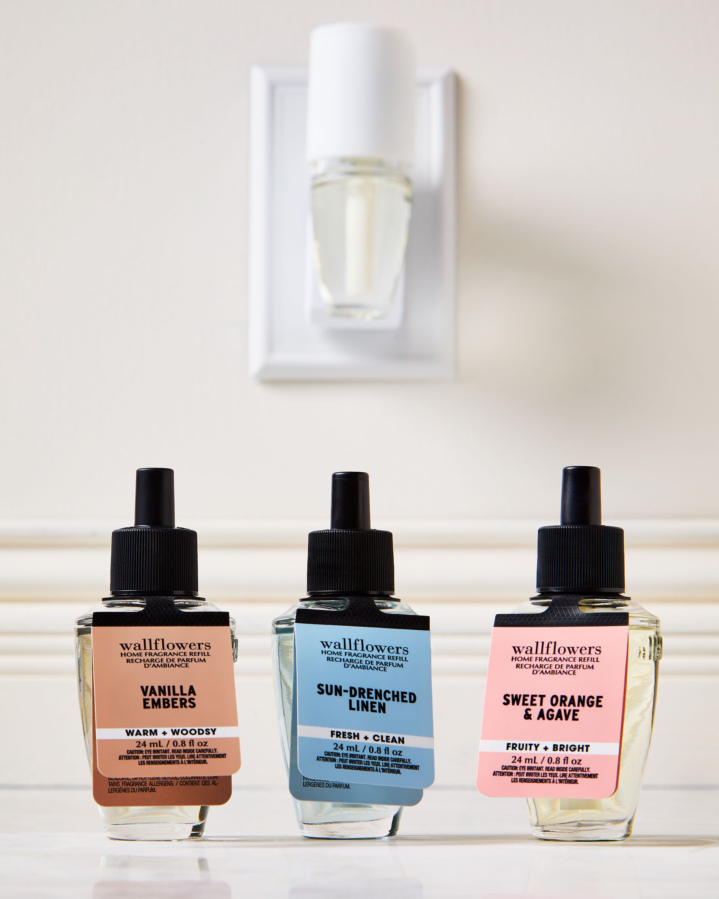 Set de reumpleri Wallflowers: Vanilla Embers, Sun‑Drenched Linen și Sweet Orange & Agave în sticluțe elegante.