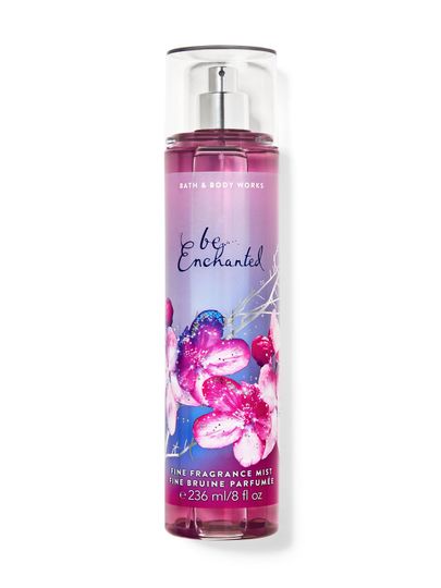 Ceață de corp "be enchanted" în sticlă roz, cu flori sclipitoare pe etichetă. Bath & Body Works.