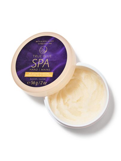 Otevřený béžový kelímek s peelingem na ruce a tmavě modrým víčkem "True Blue SPA", Bath & Body Works.