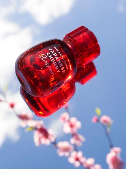 Apă de parfum Bath & Body Works Japanese Cherry Blossom în flacon roșu pe fundal cu cer și flori