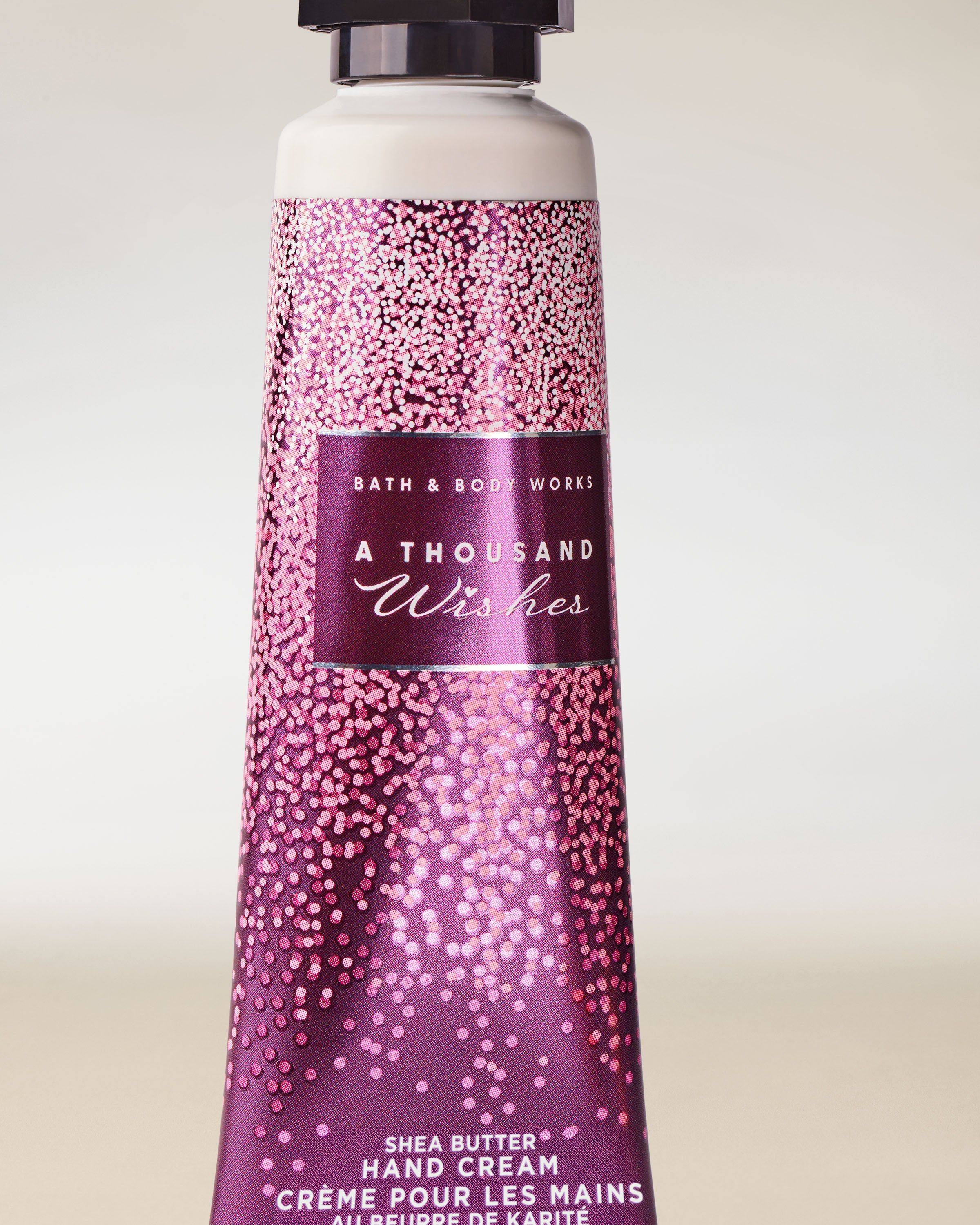 Cremă de mâini Bath & Body Works A Thousand Wishes în tub roz‑mov, 29 ml.