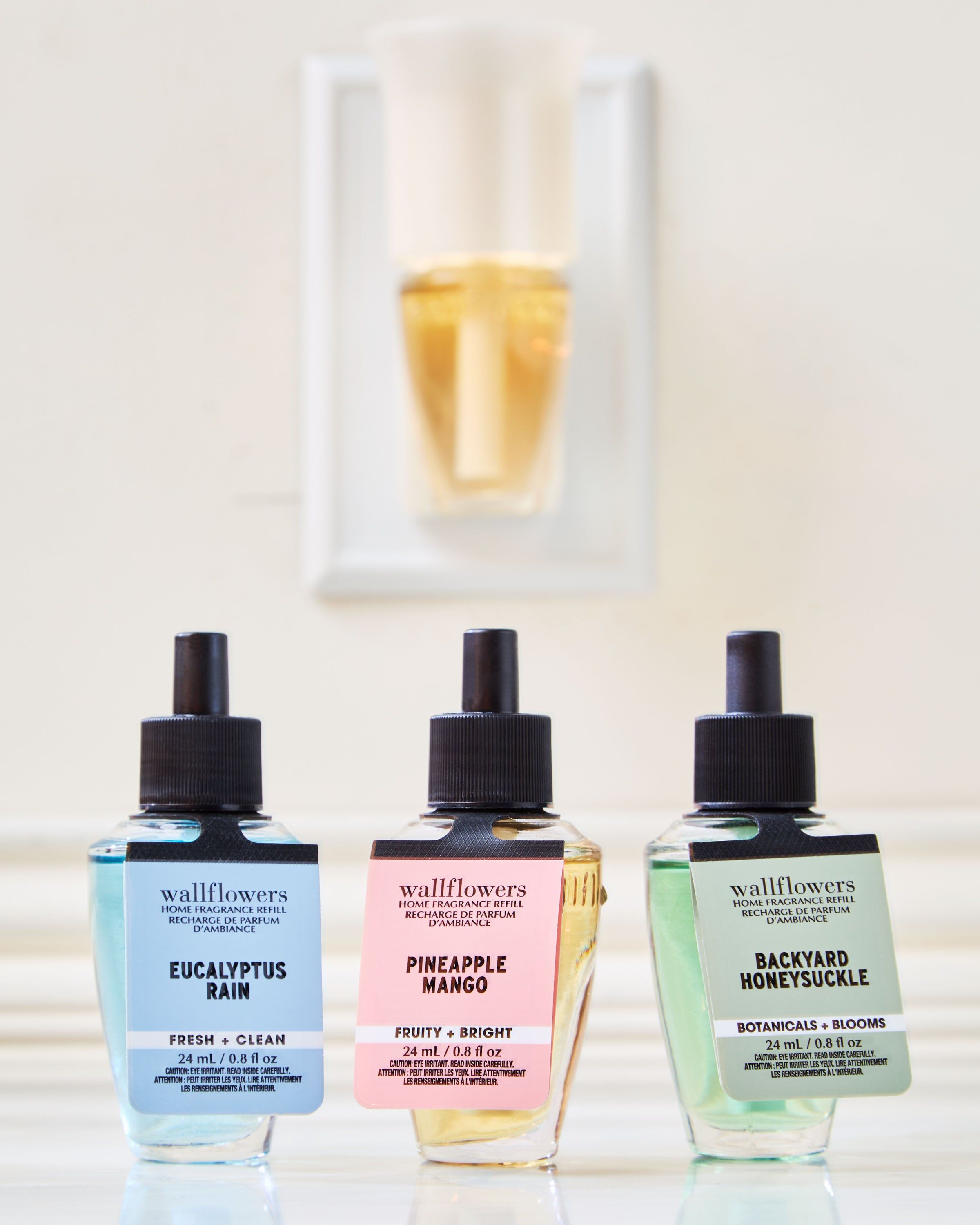 Set de reumpleri Wallflowers: Eucalyptus Rain, Pineapple Mango și Backyard Honeysuckle în sticluțe elegante.