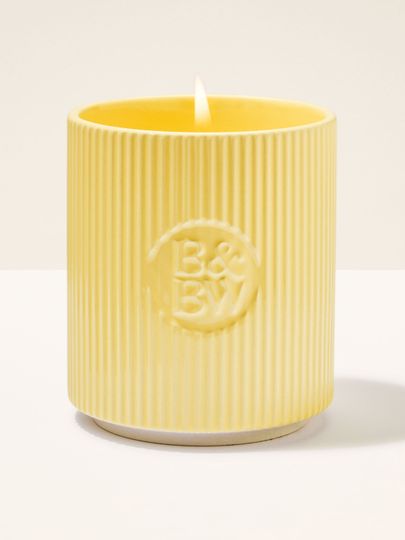 Lumânare Bath & Body Works în suport ceramic galben, cu textură striată.
