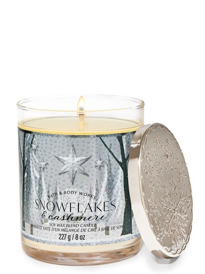Vonné svíčky „Snowflakes & Cashmere” s etiketou zobrazující zimní les se stříbrnými hvězdami, Bath & Body Works.
