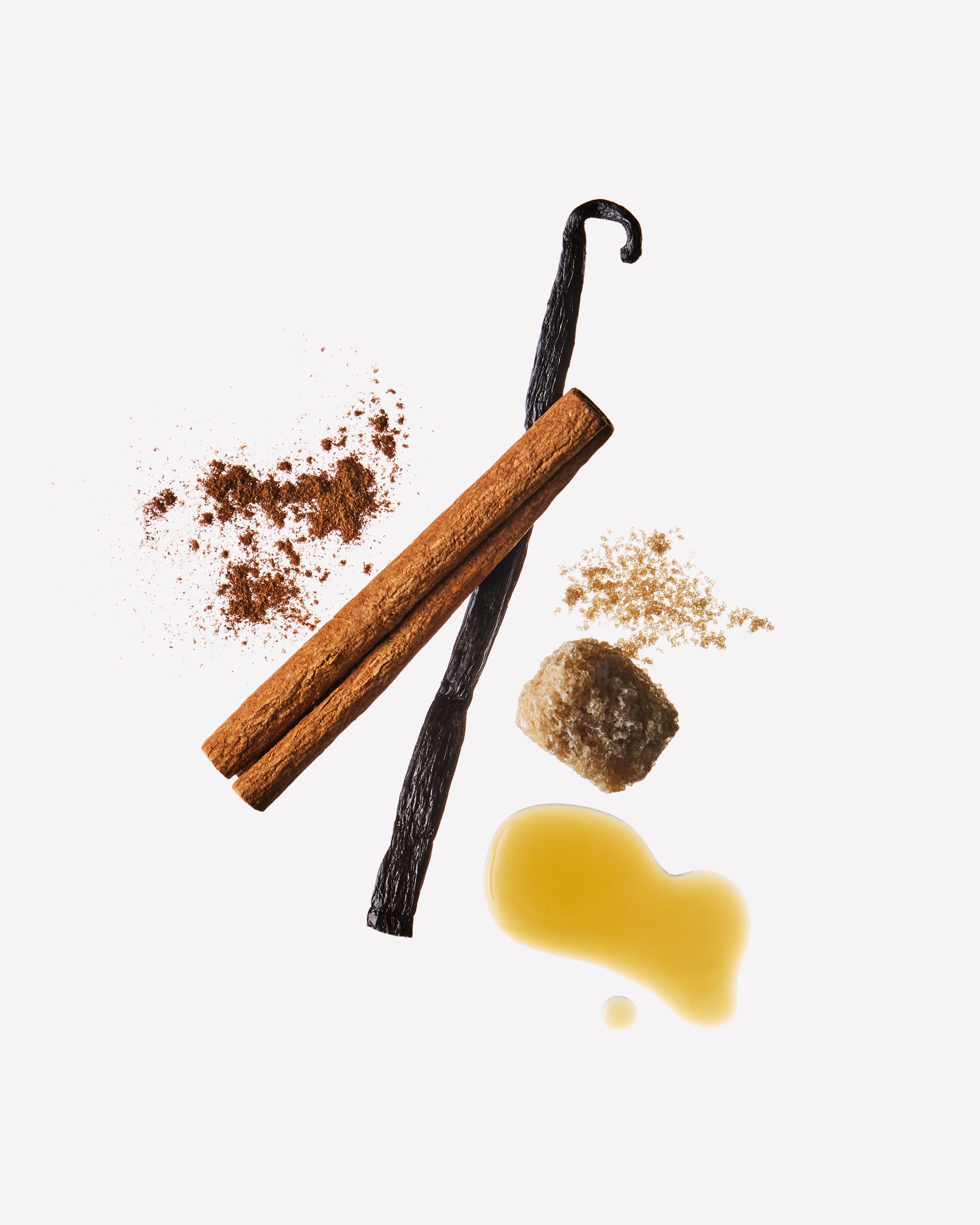 Bețe de scorțișoară, păstaie de vanilie, zahăr brun și caramel pe fundal deschis