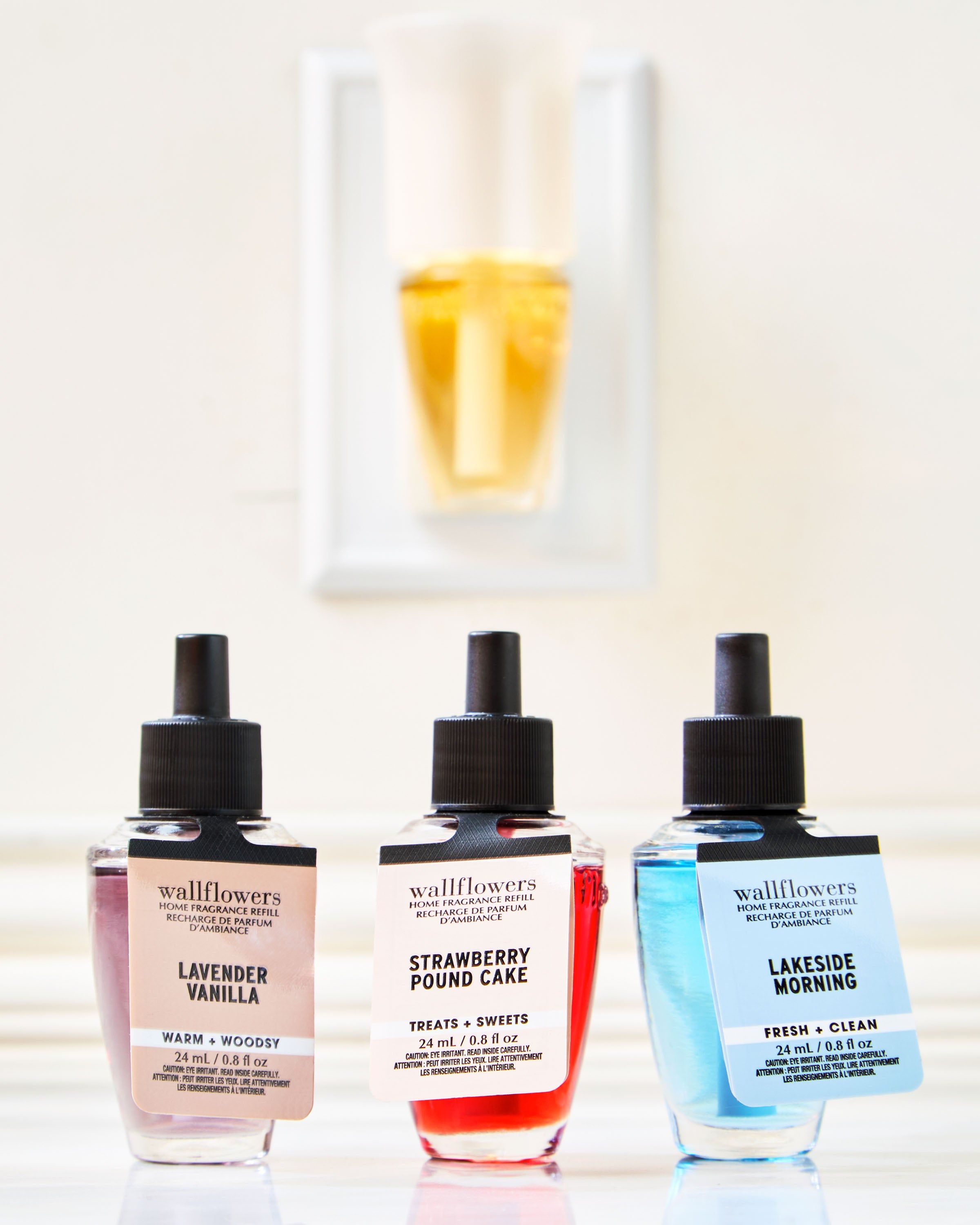 Set de trei reumpleri Wallflowers: Lavender Vanilla, Strawberry Pound Cake și Lakeside Morning în fața difuzorului.