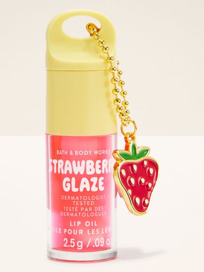 Ulei de buze Bath & Body Works Strawberry Glaze 2,5 g, în ambalaj roz cu breloc în formă de căpșună.