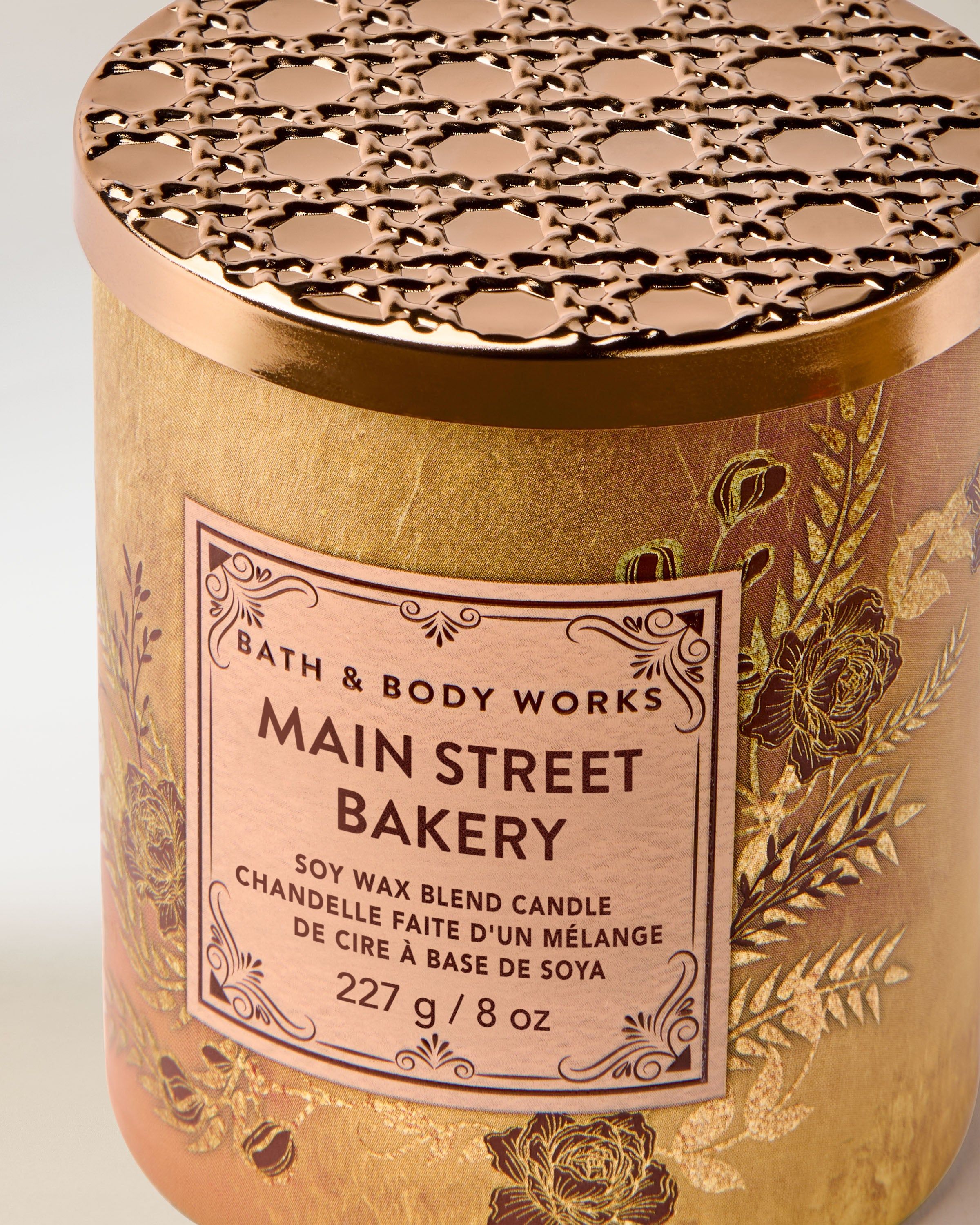 Bath & Body Works Main Street Bakery – lumânare 227 g în ambalaj auriu cu detalii botanice și capac metalic decupat.