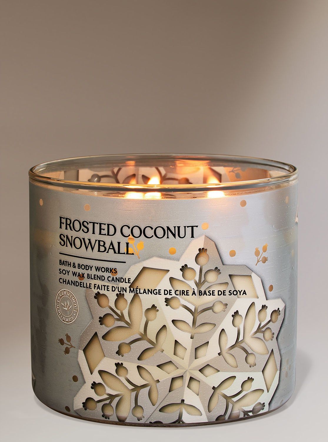 Svíčka „Frosted Coconut Snowball“ v nádobě s vyřezaným motivem stříbrné sněhové vločky, Bath & Body Works.
