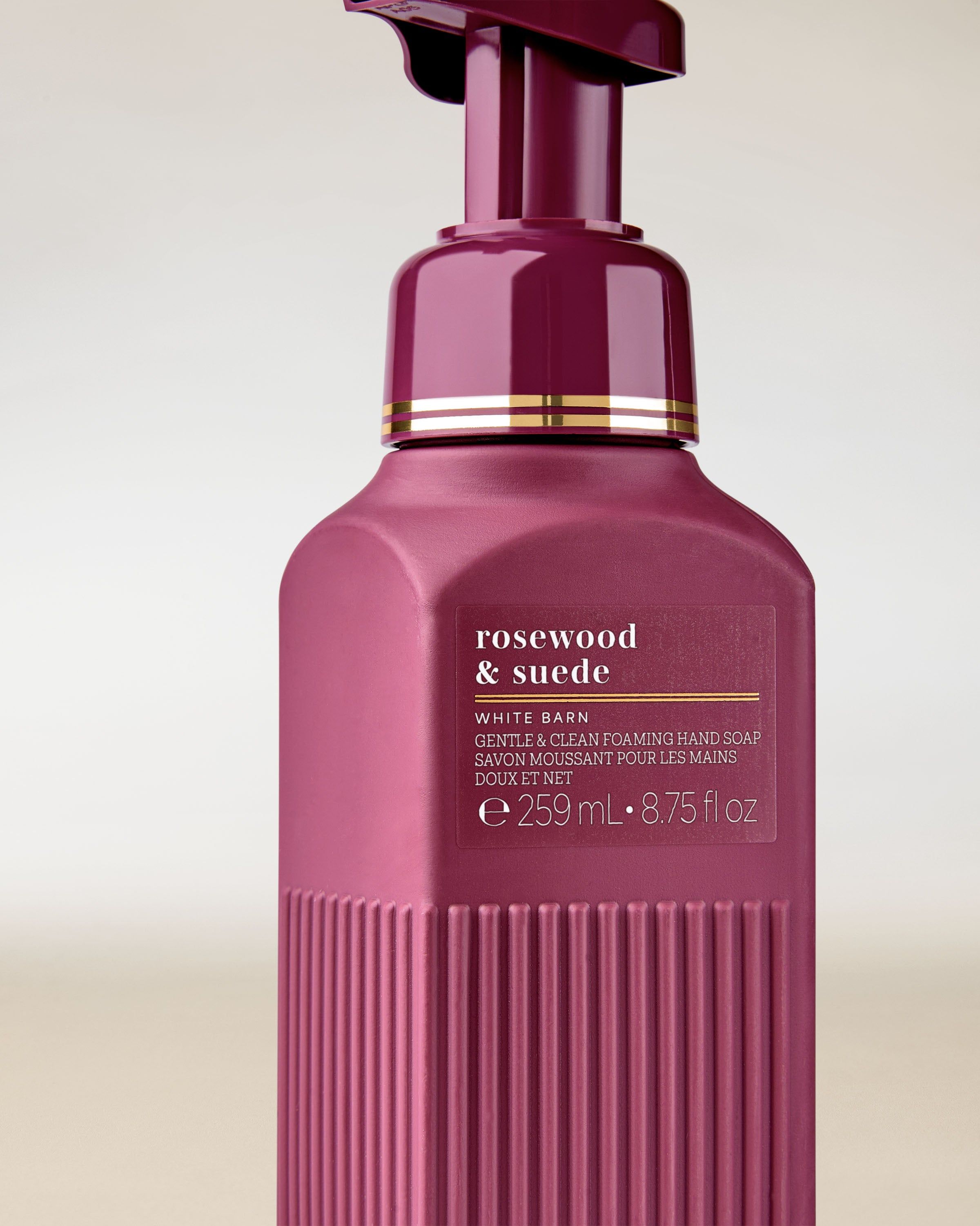 Prim-plan al săpunului spumant „Rosewood & Suede” în flacon bordo elegant.