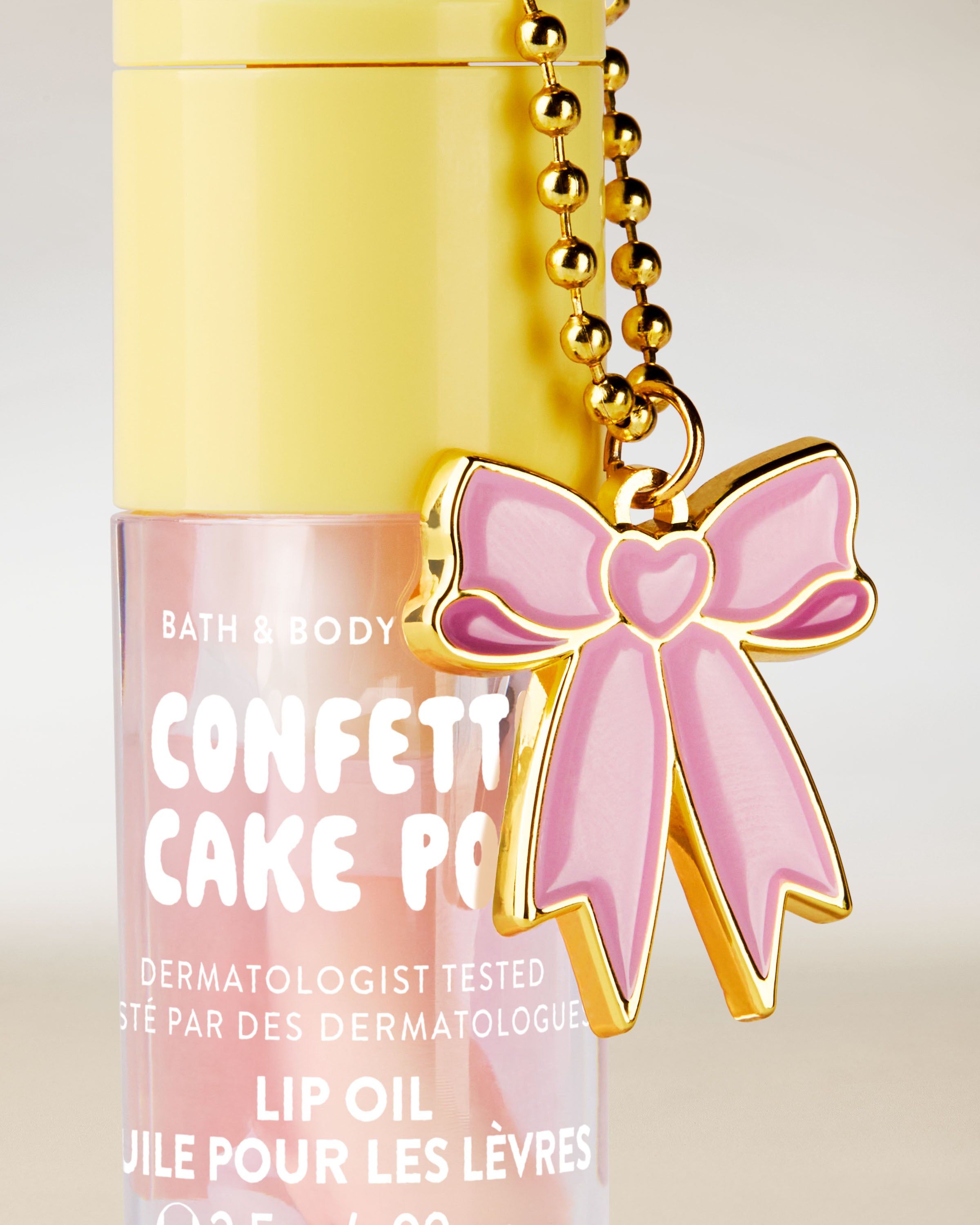 Ulei de buze Bath & Body Works Confetti Cake Pop 2,5 g, în ambalaj pastel cu breloc decorativ tip fundă.