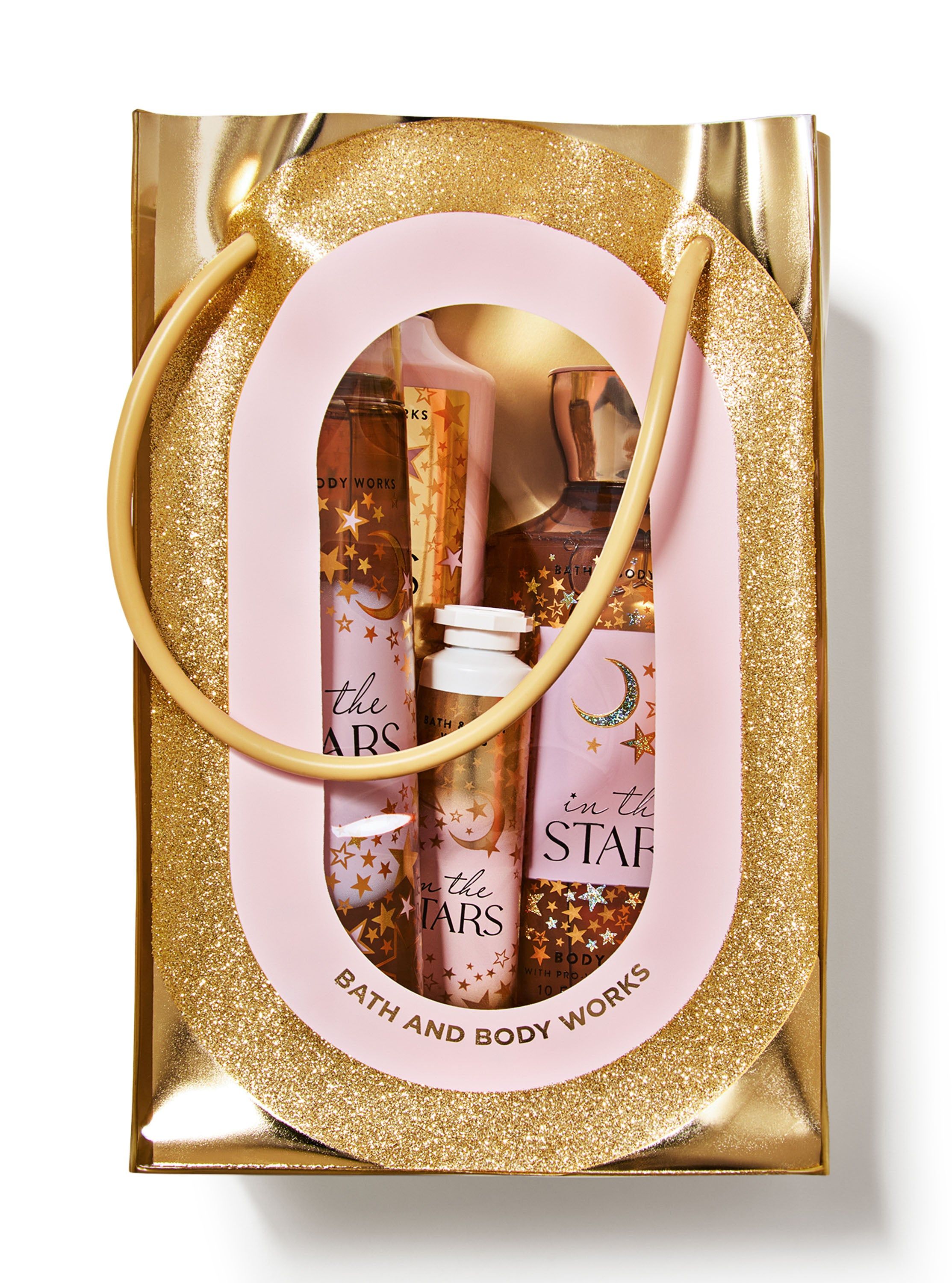 Setul Bath & Body Works In The Stars ambalat într-o pungă cadou aurie strălucitoare cu fereastră transparentă.